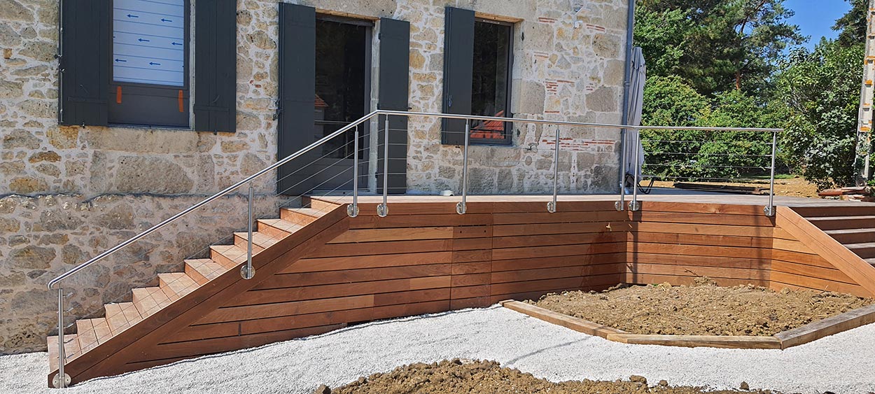 Garde-corps de terrasse en bois devant une maison en pierre